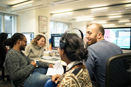 Four members of the Design102 team are chatting in the office.