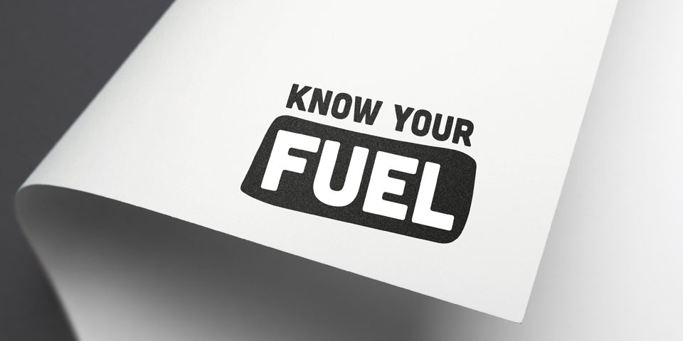 A close-up of the Know Your Fuel black and white logo mocked up on the corner of a piece of white paper.