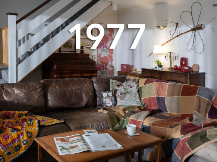 Sexual violence campaign. A messy living room. A brown leather sofa is draped in colourful blankets. An open newspaper and empty coffee cup sit on a coffee table. The date 1977 is written over the image.