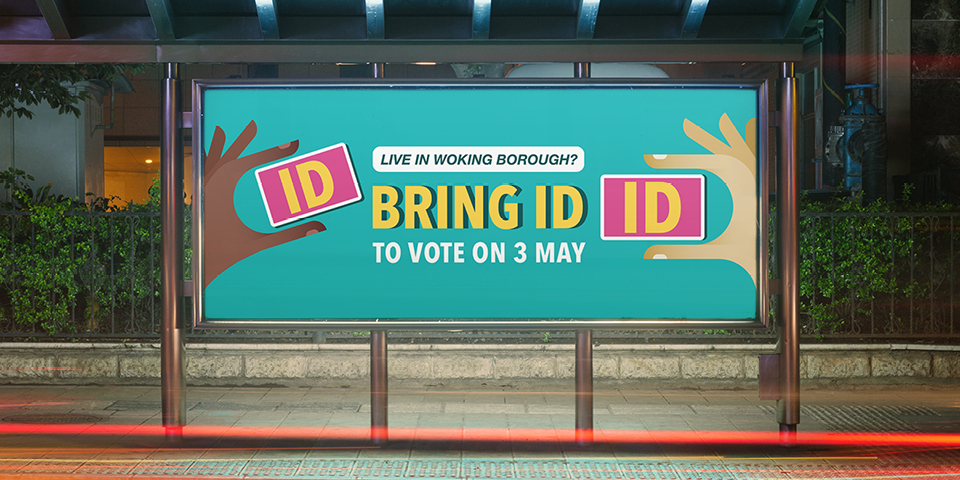 An advert within a bus stop reads: Live in Woking borough? Bring ID to vote on 3rd May.
